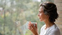 Woman drinking a cup of coffee while looking out of the window