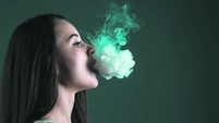 The face of vaping young woman at black studio