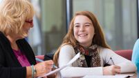 Teacher helping preteen students with homework during tutoring session