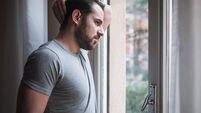 Worried man looking thoughtful out of window