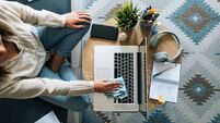 Woman wiping the surface of laptop in home office