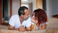 Cute middle aged european couple together in the bedroom on the bed. Man and woman in cozy lifestyle in real interior