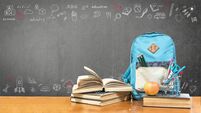 Back to school concept with school books, textbooks, backpack and stationery supplies on classroom desk with teacher's black cha