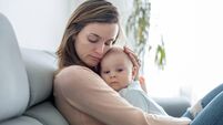 Young mother, holding her sick toddler boy, hugging him at home
