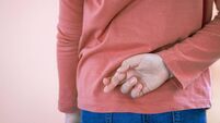 Lying concept with girl child crossing her finger behind back on light background with copy space. April Fool's Day.