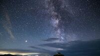 The Milky Way and night sky over St Cwyfans Church at night on Anglesey