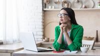 Upset young woman sitting at home with a laptop. She looks thoughtfully out the window