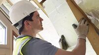 Builder Fitting Insulation Boards Into Roof Of New Home