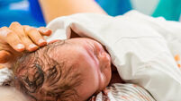 Cute newborn baby boy just after childbirth and doctor in the background