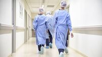 Team of medical staff in personal protective equipment walking in hospital corridor