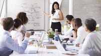 Hispanic Businesswoman Leading Meeting At Boardroom Table