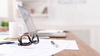 Side view of office desk with glasses, laptop and other items