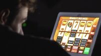 Gambling addicted man with glasses in front of online casino slot machine on laptop computer at night