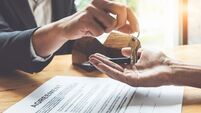 Estate agent giving house keys to customer and sign agreement in office.