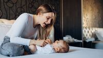 A young mother is  putting her newborn baby girl to sleep with a song