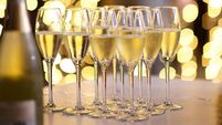 Champagne glasses with fairy string lights backdrop and a person walking passed